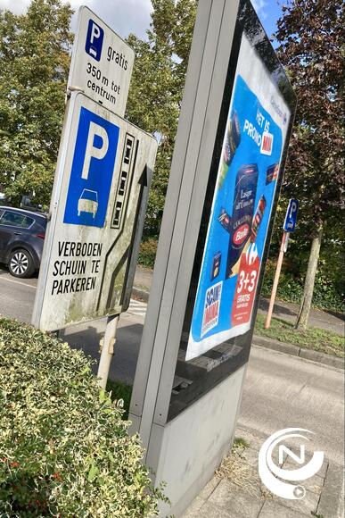 Een commercieel bord staat voor (!) een parking wegwijzerbord - en al jaren goed vuil